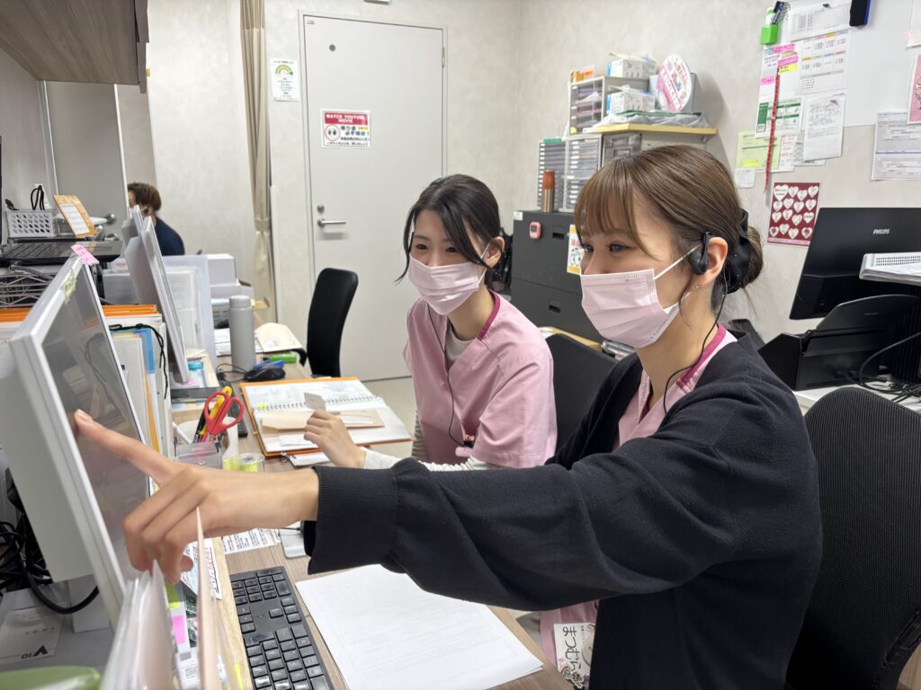 先輩スタッフが新人スタッフに受付業務を指導する様子