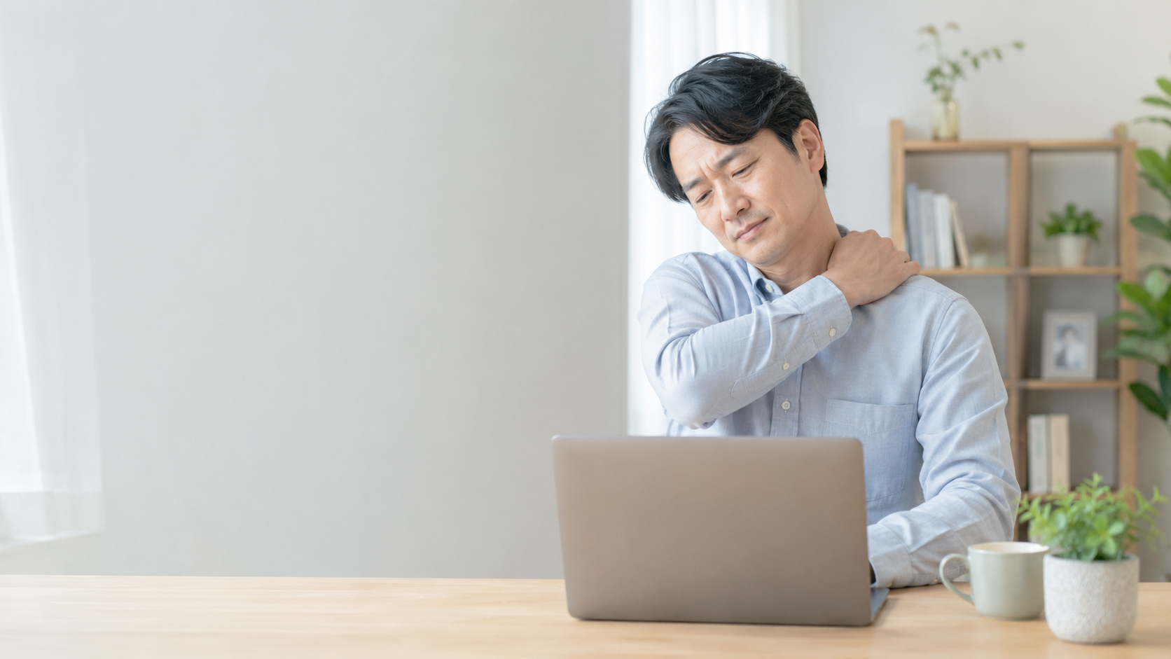 デスクワーク中に首や肩に手をあてている様子（イメージ）