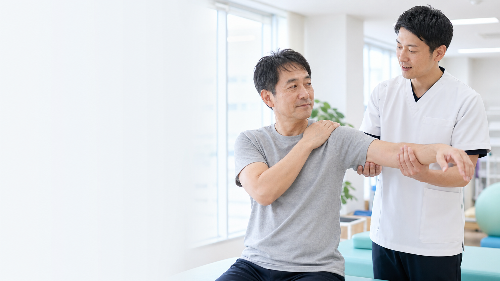 五十肩の患者に肩の動かし方を説明する理学療法士