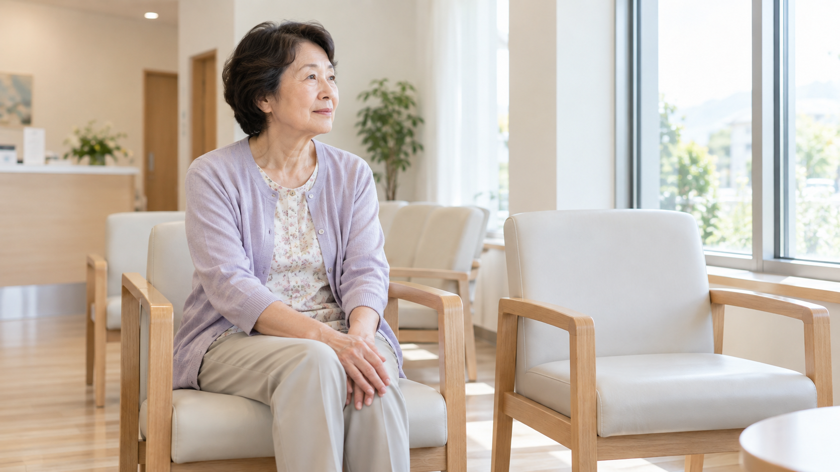 クリニックの待合室で、ひざに手を置いて座っている様子（イメージ）